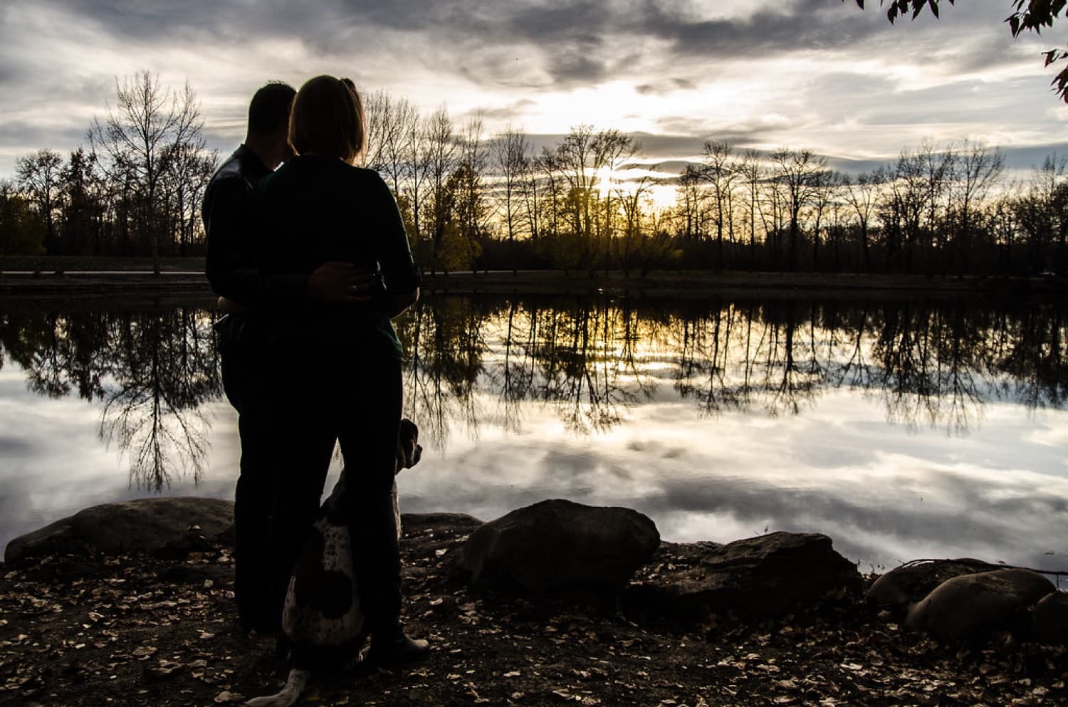 Couple silhouetted against a prairie sunset by the water