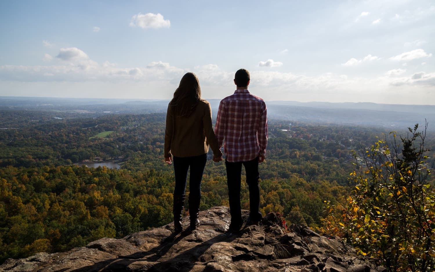Couple holding hands on a mountain overlook in autumn