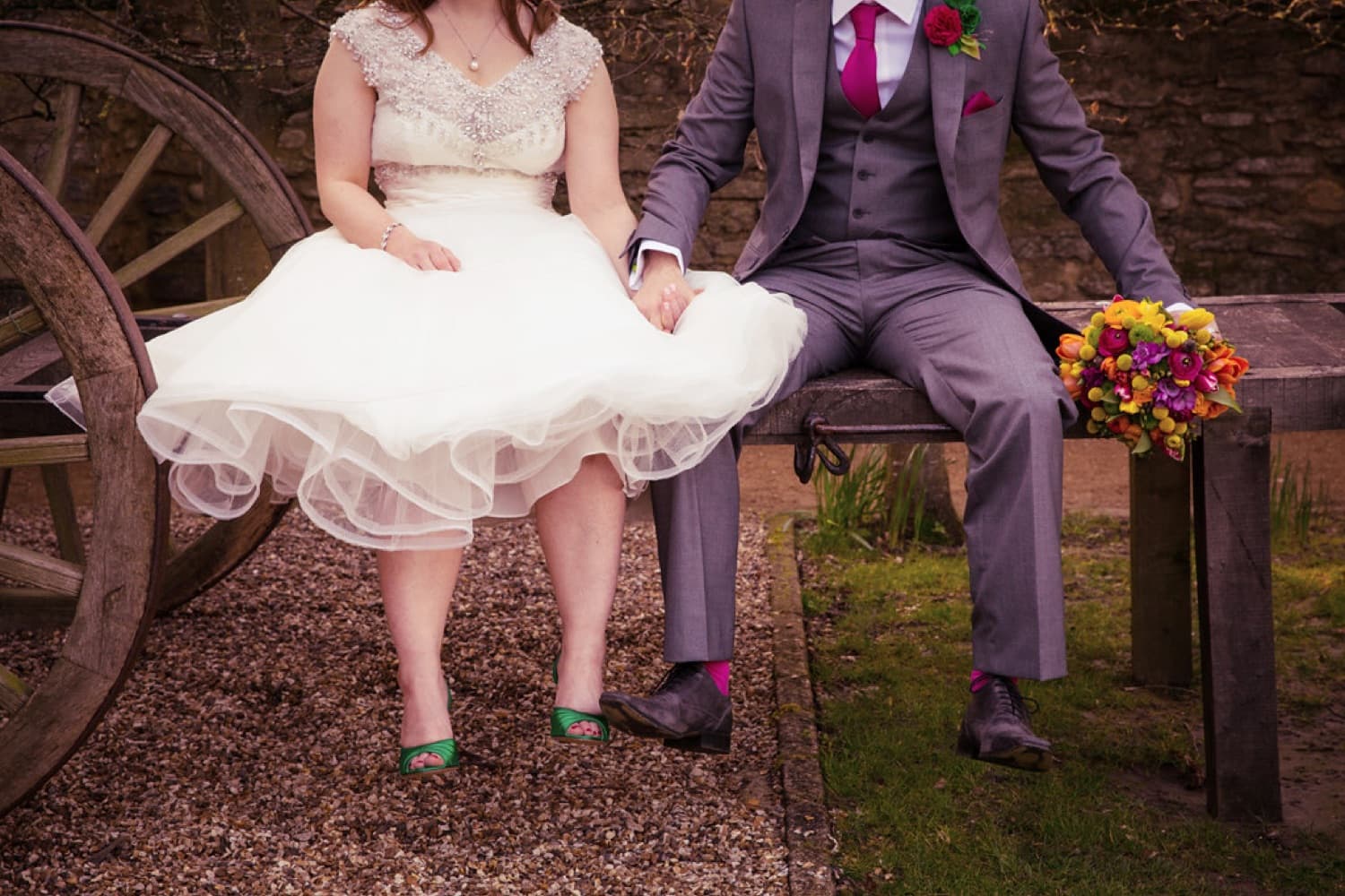 Wedding detail — joined hands and a bright bouquet